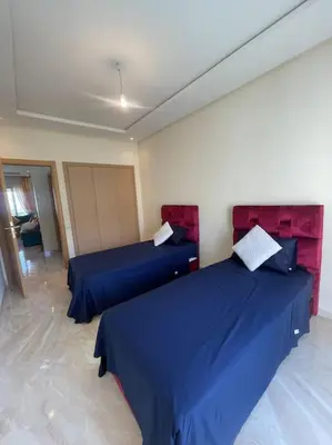 two beds in a room with blue sheets at Appart avec Piscine Proche de la Mer in Bouznika