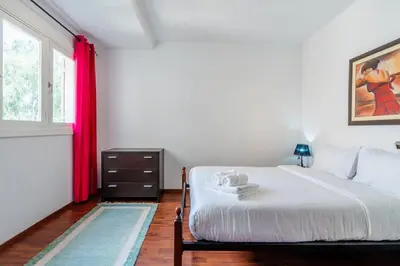 a bedroom with a bed with red curtains and a window at Appartement Cosy Proche du Stade in Rabat