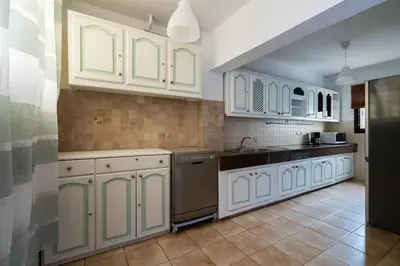 a kitchen with white cabinets and a black refrigerator at Appartement Cosy Proche du Stade in Rabat