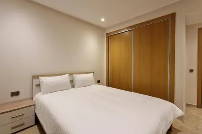 a bedroom with a white bed and a wooden closet at Cosy Aparts, 2BR, downtown, near tramway in Casablanca