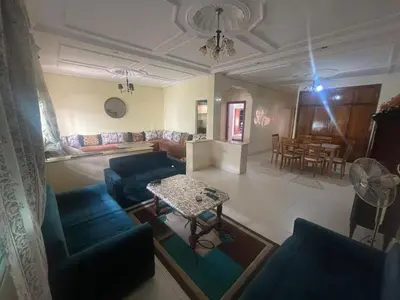 a living room with blue couches and a table at Appt à Harhoura in El Harhoura