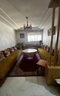 a living room with a couch and a table at Appartement vues piscine in Mansouria