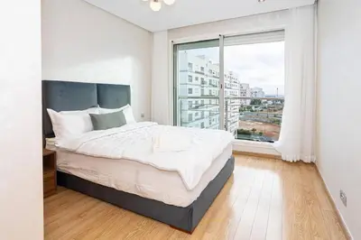 a bedroom with a large bed and a large window at Appartement géant in Rabat
