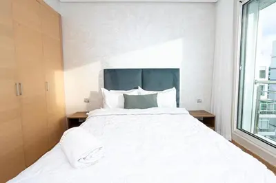 a bedroom with a large white bed with a window at Appartement géant in Rabat