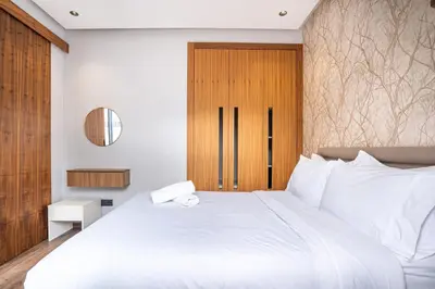a bedroom with a white bed and a wooden door at Central, confort & luxueux 1room - quartier Princesses in Casablanca