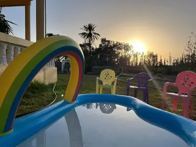 a pool with chairs and a rainbow in a backyard at Countryside's Tiny House in O Ben Slimane