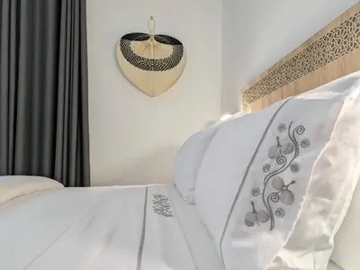 a white bed with a heart hanging on a wall at Hôtel Les Remparts in Azemmour
