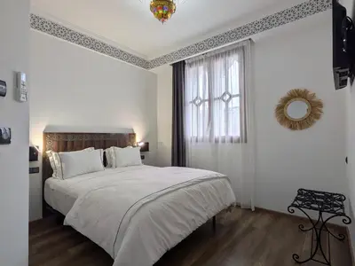 a white bedroom with a large bed and a window at Hôtel Les Remparts in Azemmour