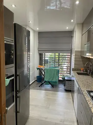 a kitchen with a stainless steel refrigerator and a table at Rock Island Haut standing in Mohammedia
