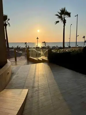 a sunset over a beach with palm trees and the ocean at Rock Island Haut standing in Mohammedia