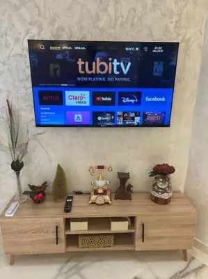 a television hanging on a wall above a wooden table at Cozy appartement Rabat in Rabat