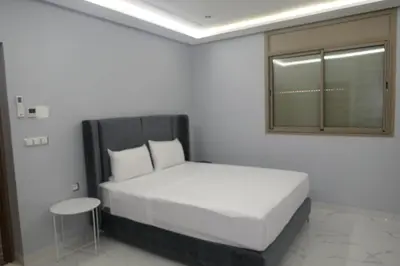 a white bedroom with a bed and a table at Les portes de Temara in Temara