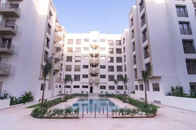 an apartment building with a swimming pool in front of it at Studio Meuble a 5 min de l'aéroport Casablanca in Nouaceur