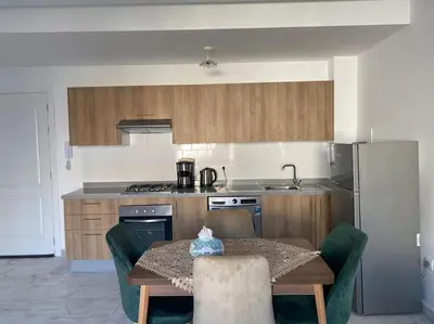 a kitchen with a table with chairs and a refrigerator at Studio Meuble a 5 min de l'aéroport Casablanca in Nouaceur