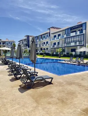 a row of lounge chairs and umbrellas next to a swimming pool at Les crêtes dar bouazza in Casablanca
