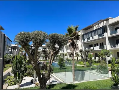an apartment complex with a swimming pool and palm trees at Les crêtes dar bouazza in Casablanca