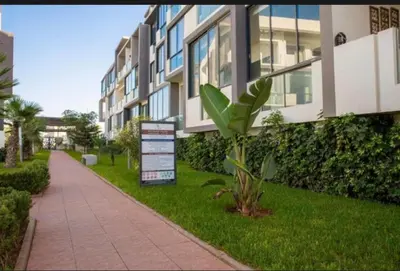 a building with a sign in the grass next to a sidewalk at Les crêtes dar bouazza in Casablanca