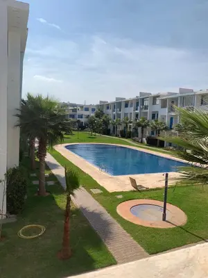 a swimming pool with palm trees next to a building at Résidence Perla Andalusia Vue Sur Mer in Mansouria