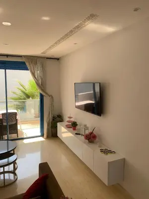 a living room with a tv on a white wall at Résidence Perla Andalusia Vue Sur Mer in Mansouria