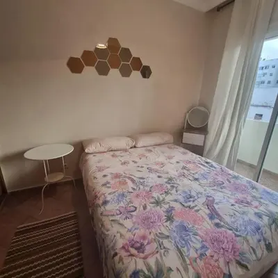 a bedroom with a bed and a table and a window at Appartement lumineux by Moon in Casablanca