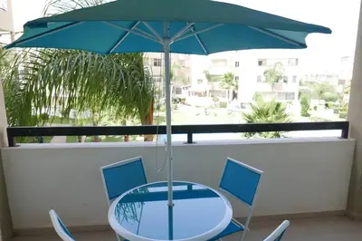 a table and chairs with a blue umbrella on a balcony at Appartement Haut Standing - Bouznika plage in Bouznika