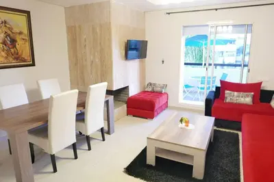 a living room with a table and a red couch at Appartement Haut Standing - Bouznika plage in Bouznika