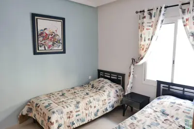 a bedroom with two beds and a window at Appartement Haut Standing - Bouznika plage in Bouznika