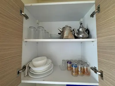 a cupboard with plates and bowls and glass jars at Sublime appart piscines & espaces jeux, proche mer in Bouznika