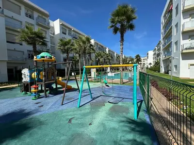 a playground with a play equipment in a city at Sublime appart piscines & espaces jeux, proche mer in Bouznika