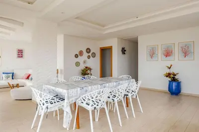 a white dining room with a table and chairs at Beachfront Escape - Panoramic View and Spacious Terrace in Skhirat