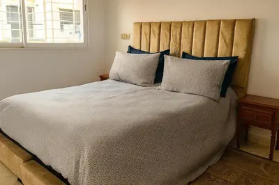 a bedroom with a large bed with blue pillows at Spacious & Comfy Moroccan Apartment in Temara