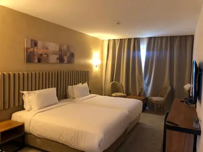 a hotel room with a large bed and a television at Hôtel Hariz Son in Berrechid