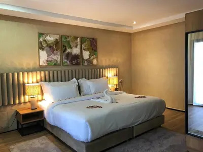 a bedroom with a large white bed with two lamps at Hôtel Hariz Son in Berrechid