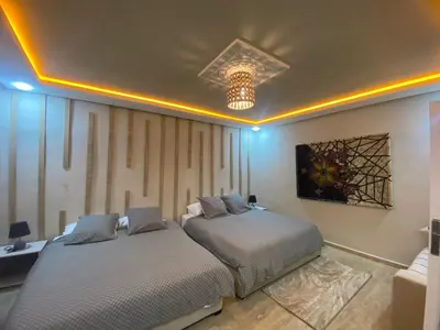 a bedroom with two beds and a chandelier at Un écrin rabati in Rabat