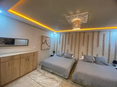 a bedroom with two beds and a tv on the wall at Un écrin rabati in Rabat