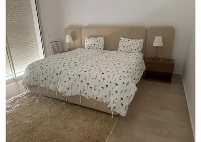 a bedroom with a bed with a comforter and two lamps at Villa luxe avec piscine in Oulad Hamida