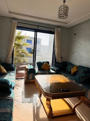 a living room with a table and a couch at Bel Appartement vue piscine in Mansouria