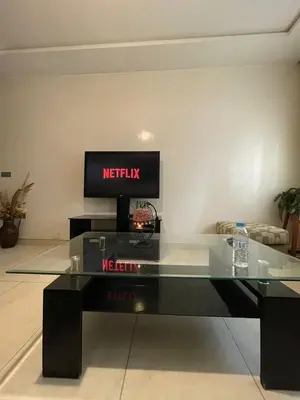a living room with a glass table with a television at residence rania in Maarif