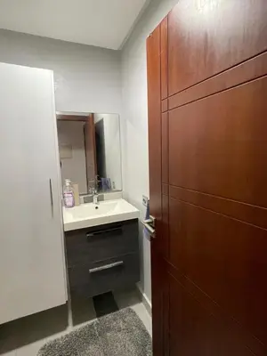 a bathroom with a sink and a large wooden cabinet at residence rania in Maarif