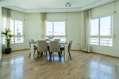 a dining room with a table and chairs and windows at Appartement à Maarif, Proche du Twin et McDonald's in Casablanca