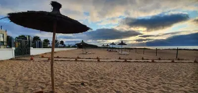 a beach with umbrellas and chairs on the sand at Superbe Appartement pieds dans l'eau - Résidence GARDENBAY in Dar Mohammed Ould Haj Jilali