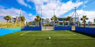 a tennis court with a tennis ball on the grass at Superbe Appartement pieds dans l'eau - Résidence GARDENBAY in Dar Mohammed Ould Haj Jilali