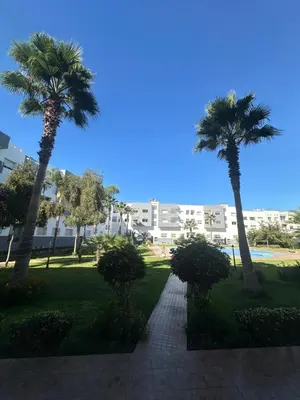 a walkway with palm trees in a park at Appartement corniche d'or, Mohammedia in Mohammedia