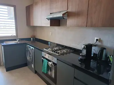 a kitchen with a stove and a washing machine at Appartement spacieux 3 chambres avec parking privé in Nouaceur