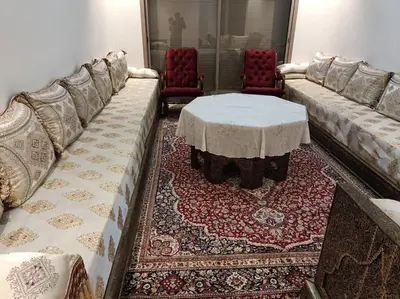 a living room with couches and a table and chairs at Appartement spacieux 3 chambres avec parking privé in Nouaceur