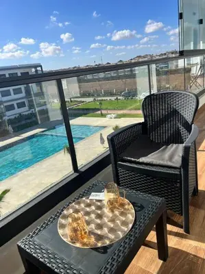 a balcony with a table and a chair and a pool at Appartement - EL Mansouria - Mohammadia - Bouznika in Mansouria