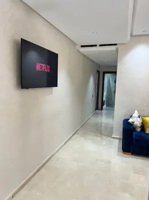 a room with a tv on the wall and a blue couch at Appartement - EL Mansouria - Mohammadia - Bouznika in Mansouria