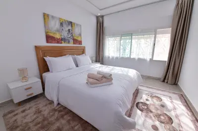 a bedroom with a white bed with a purse on it at Cozy Duplex appartement wifi parking proximité in Rabat