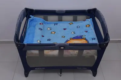an open baby crib with a blue blanket in it at Cozy Duplex appartement wifi parking proximité in Rabat