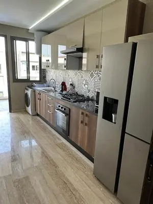 a large kitchen with a refrigerator and a stove at les crêtes dar bouazza in Tamaris